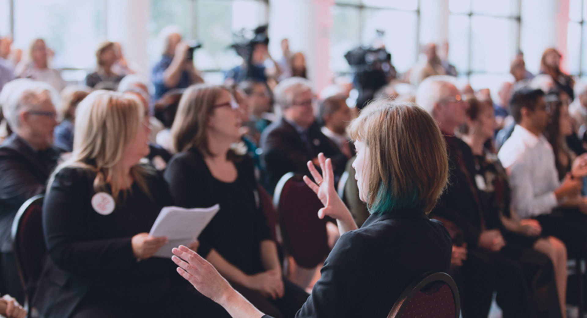 A crowd of people all looking in the same direction watching a presentation at an in-person event